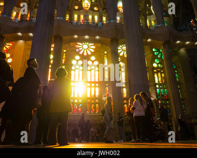 Sera La luce del sole è in arrivo attraverso le finestre verniciate della facciata occidentale di La Sagrada Familia di Barcellona cattedrale che è affollata di turisti Foto Stock