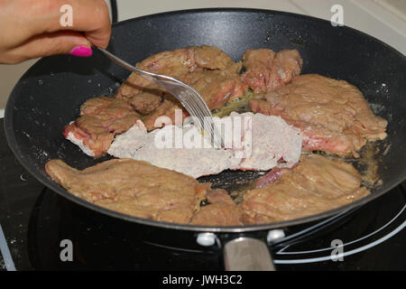 La cottura della carne in padella su piastra ad induzione Foto Stock