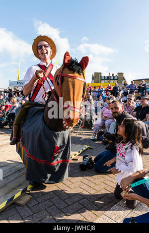 Broadstairs annuale settimana Folk Festival. Uomo di equitazione cavallo hobby, la Harwich Morris bestia, fool, davanti al pubblico e i bambini. Una giovane ragazza bambino arrivando a toccare la testa del cavallo. Foto Stock