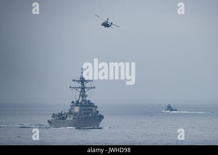 Oceano Pacifico. 11 Ago, 2017. Un U.S. Navy MH-60S Seahawk elicottero sorvola la Arleigh Burke-class guidato-missile destroyer USS Wayne E. Meyer durante il transito dello stretto di mostrare la forza di esercizio con Theodore Roosevelt Carrier Strike gruppo 11 agosto 2017 nell'Oceano Pacifico. La formazione avviene durante la tensione elevata con la Corea del Nord. Credito: Planetpix/Alamy Live News Foto Stock