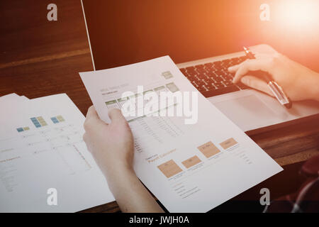 Le mani di imprenditore lavorando sul computer portatile con dati grafici sulla scrivania in legno Foto Stock