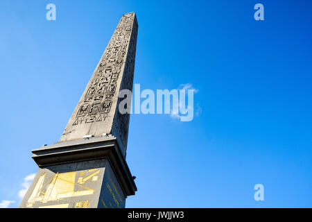 Vista a basso angolo dell'obelisco di Luxor in piazza Concorde a Parigi, con geroglifici e diagrammi dorati sul piedistallo, contro il cielo blu. Foto Stock