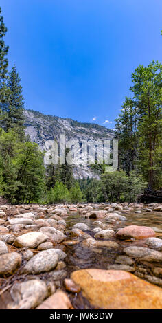 Flusso in Yosemite con fondali rocciosi. Modi di acqua in Yosemite con la foresta circostante Foto Stock