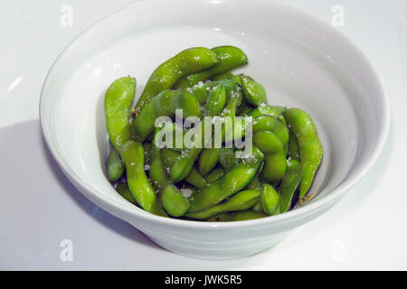 Verde edamame cotto a vapore in una ciotola bianco Foto Stock