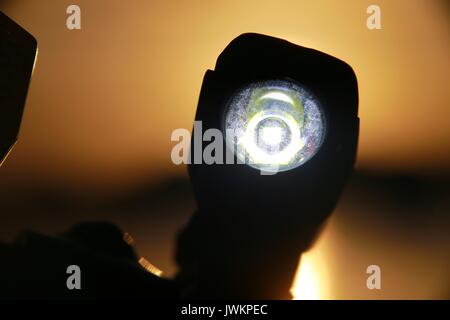 Luce per biciclette illuminata sul manubrio contro il tramonto sul lago Foto Stock