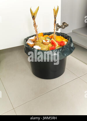 Separare la procedura di garbage collection. I rifiuti organici in nero la benna e il sacchetto di plastica. Foto Stock