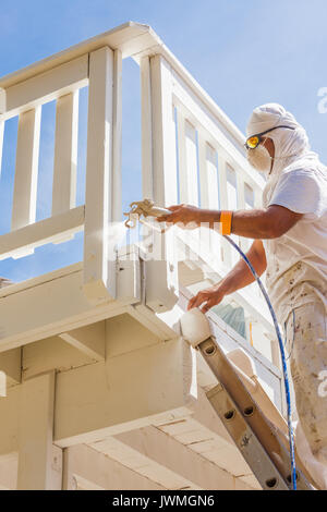 Professional pittore casa indossando la protezione del viso la verniciatura a spruzzo ponte di una casa. Foto Stock