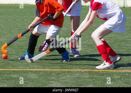 Bambini che giocano Campo di hockey a prezzi competitivi. Due ragazze defender impegnativo boy utente malintenzionato Foto Stock