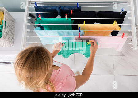 Elevato angolo di visione della donna appesa bagnato panno pulito sulla linea di abbigliamento in lavanderia Foto Stock