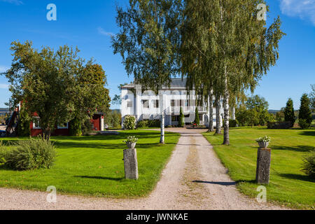 Agriturismo e strada. White cottage di legno con alberi. Hedemora, Svezia Foto Stock