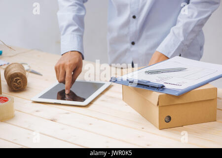 Il liberatore di maschio con la compressa sul posto di lavoro in un ufficio postale Foto Stock