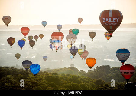 I palloni ad aria calda passa il puntatore del mouse su Long Ashton, Bristol, durante la salita di massa, dove mongolfiere provenienti da tutto il mondo si riuniranno a Ashton Court, Bristol, a prendere parte al Bristol International Balloon Fiesta. Foto Stock