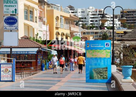 I turisti a piedi passato bar e negozi lungo la promenade, Torremolinos, provincia di Malaga, Andalusia, Spagna, Europa occidentale. Foto Stock