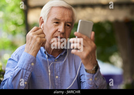 Ritratto di imprenditore senior con la video chiamata tramite smartphone in outdoor cafe lounge Foto Stock