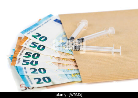 Siringhe e le banconote in euro le fatture in busta marrone. Costo della salute, della medicina, il traffico di droga. Close-up. Foto Stock
