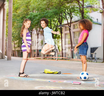 Ragazzo salta con gli amici dopo la scuola su manto elastico giocando yoki gioco Foto Stock