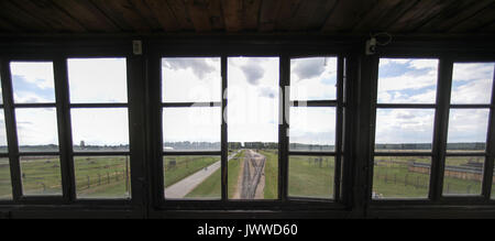 I visitatori a piedi in tutta l'ex campo di concentramento di Auschwitz-Birkenau Oswiecim, Polonia, 26 giugno 2017, fotografata attraverso una finestra della torre di avvistamento. La grande organizzazione paramilitare nella Germania nazista, SS (Schutzstaffel, lit. "Protezione squadrone"), ha eseguito la concentrazione e la morte camp tra 1940 e 1945. Deportati in entrata sono stati selezionati in diversi gruppi sulla rampa tra le tracce subito dopo sono arrivati a Birkenau. Le persone che non erano in grado di lavorare (anziani, deboli, le donne e i bambini) talvolta sono stati inviati alle camere a gas direttamente senza registrazione. Circa 1,1 A Foto Stock