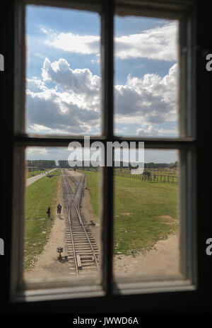 I visitatori a piedi in tutta l'ex campo di concentramento di Auschwitz-Birkenau Oswiecim, Polonia, 26 giugno 2017, fotografata attraverso una finestra della torre di avvistamento. La grande organizzazione paramilitare nella Germania nazista, SS (Schutzstaffel, lit. "Protezione squadrone"), ha eseguito la concentrazione e la morte camp tra 1940 e 1945. Deportati in entrata sono stati selezionati in diversi gruppi sulla rampa tra le tracce subito dopo sono arrivati a Birkenau. Le persone che non erano in grado di lavorare (anziani, deboli, le donne e i bambini) talvolta sono stati inviati alle camere a gas direttamente senza registrazione. Circa 1,1 A Foto Stock