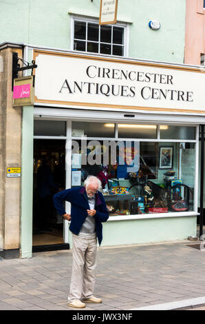 Un vecchio / anziani / senior uomo in piedi al di fuori del centro di antiquariato in Cotswolds città di CIRENCESTER, GLOUCESTERSHIRE, Inghilterra, Regno Unito. Foto Stock