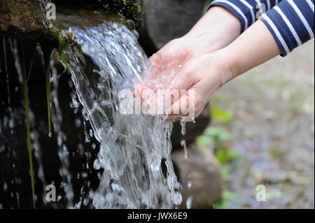 Versare acqua nella donna la mano sulla natura sfondo Foto Stock