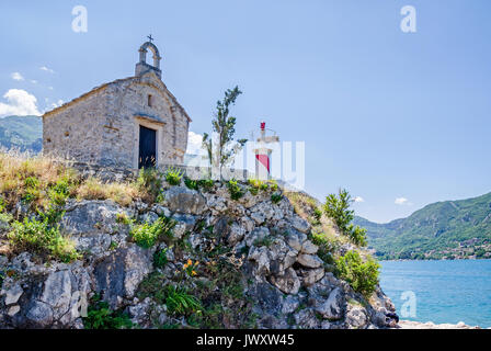 Una piccola vecchia cappella e una torre faro dell'Istituto di Biologia Marina di Kotor, Montenegro Foto Stock
