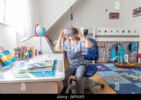 Little Boy, 7 anni, gioca un 3-D gioco per computer con una realtà virtuale la cuffia nella sua camera per bambini, Foto Stock