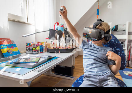 Little Boy, 7 anni, gioca un 3-D gioco per computer con una realtà virtuale la cuffia nella sua camera per bambini, Foto Stock