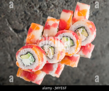 Rotolo realizzato con tonno, salmone e capesante su sfondo di calcestruzzo Foto Stock