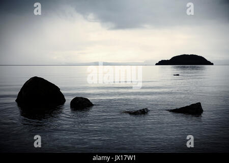 Serena moody rocce lago Taupo con Motutaiko Isola Foto Stock