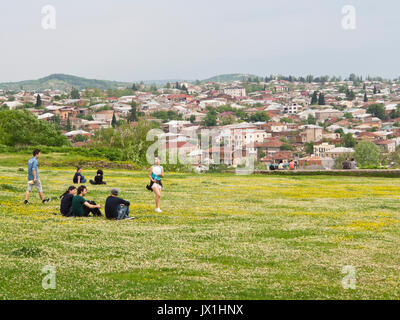 Vista della città di Kutaisi in Georgia dalla cima della collina dalla cattedrale di Bagrati, primavera, la gioventù rilassante su un tappeto di fiori selvatici Foto Stock