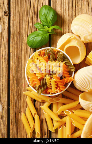 Vari tipi di pasta essiccata su sfondo di legno Foto Stock