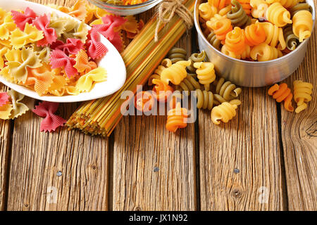 Vari tipi di pasta colorata su un sfondo di legno Foto Stock