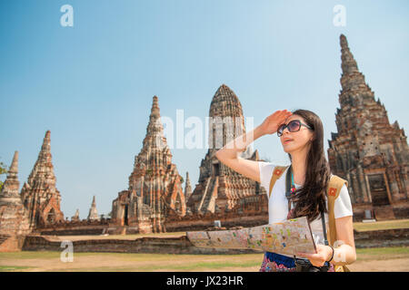 Giovane donna in abiti eleganti azienda mappa della città mentre in piedi nel villaggio di Ayutthaya a Bangkok, Thailandia, cercando per la prossima stazione famosa posizione wi Foto Stock