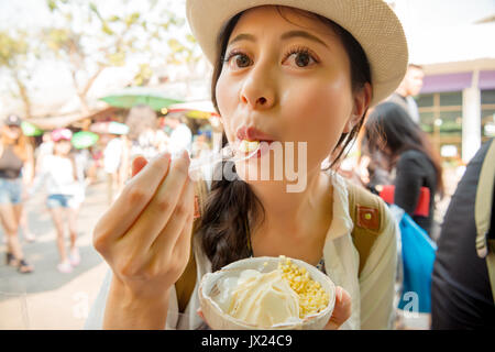 Primo piano immagine ritratto di viaggiatori femmina mangiare godendo di cocco popolare gelato sul viaggio thailandia vacanze nel famoso del fine settimana di Chatuchak marke Foto Stock