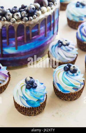 Luminose blu festosa torta con frutti di bosco e il cioccolato e tortine con crema di latte . Foto Stock