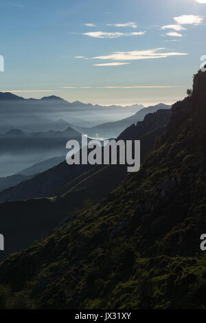 La mattina presto l'alba sul Cabrales valley con la nebbia e il fumo degli incendi in abitazioni locali cast di luce straordinari, Picos de Europa, Asturias, Spagna. Foto Stock