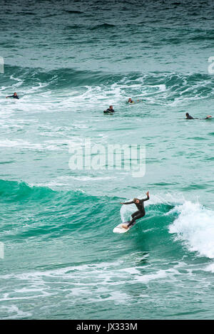 Navigare in UK. Un surfista a cavallo di un onda al Fistral in Newquay, Cornwall. Foto Stock