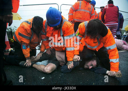 Il personale di sicurezza violentemente tentare di impedire le protezioni del clima di lock-in e bloccare i cancelli a Quadrilla fracking del sito in Lancashire. Foto Stock