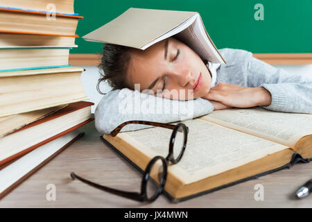 Stanco giovane allievo si è addormentato tra libri. Foto della bambina nella scuola. Si torna a scuola! Foto Stock