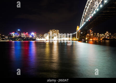 Luce colorata riflessione a Sydney Harbour Bridge di notte da Circular Quay, Sydney, Australia Foto Stock