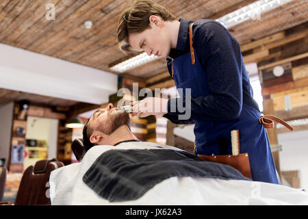 L uomo e il barbiere con trimmer il taglio di barba di salon Foto Stock