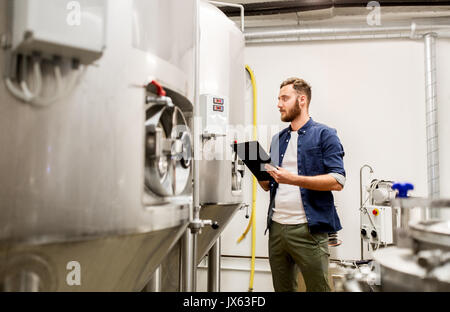 Uomo con appunti alla birreria artigianale o impianto di birra Foto Stock