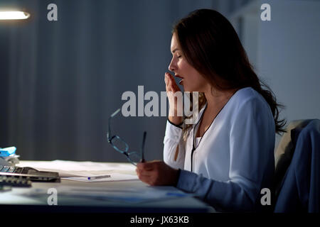 Stanco della donna con gli occhiali a sbadigliare di notte office Foto Stock