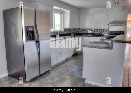 Carino e moderno stile agriturismo cucina con isola, e acciaio inossidabile frigorifero e armadietti di bianco in un'abitazione. Foto Stock