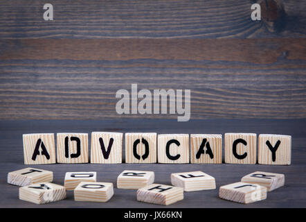 Advocacy parola scritta sul blocco di legno. Legno scuro dello sfondo con texture. Foto Stock