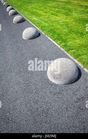 Abstract sfondo costituito di pavimento di asfalto, Prato e la fila di emisfero barriere. Foto Stock