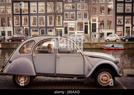 Vintage Citroen 2CV parcheggiate lungo un canale di Amsterdam (Paesi Bassi). Marzo 2015. formato paesaggio. Foto Stock