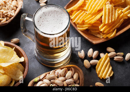 Lager boccale di birra e spuntini sul tavolo di pietra. Dadi, chips Foto Stock