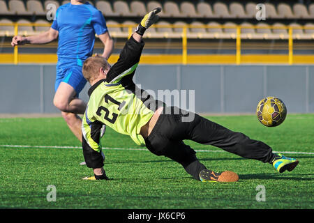 Il portiere saltando alla cattura di palla. Giocatore di football e salto di portiere sul campo di Stadium. Il portiere afferra la palla. Giocatore di football Foto Stock