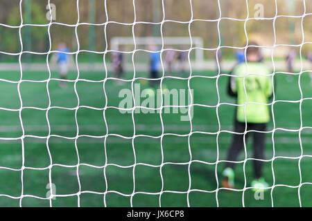 Il portiere si erge contro obiettivo con net e Stadium. Porta di calcio net. Soccer net gate. In sfondo sfocato stand un portiere. Alle spalle di obiettivo di socce Foto Stock